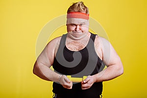 Fat man try to lift small yellow dambbell