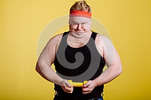 Fat man try to lift small yellow dambbell
