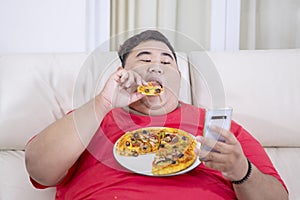 Fat man using his phone while gawking at a pizza