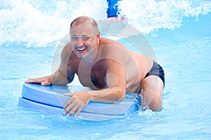 Fat man on a water Board on the water. Happy adult man floating on the waves.