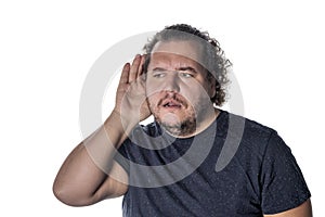 Fat man wearing a casual outfit, trying to hear someone putting his hand on his ear, standing on a white background