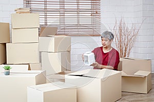 Fat man with white hair is packing products into paper boxes for delivery