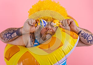 Fat man with wig in head is ready to swim with a donut lifesaver