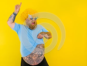 Fat man with wig in head and sunglasses dances