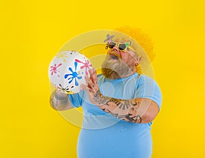 Fat man with wig in head and sunglasses have fun with a ball