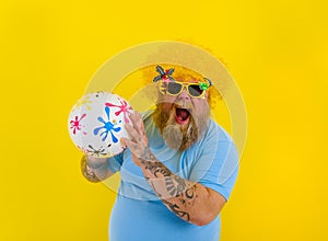 Fat man with wig in head and sunglasses have fun with a ball