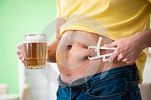 The fat obese man holding beer in dieting concept