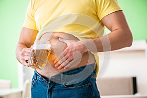 The fat obese man holding beer in dieting concept