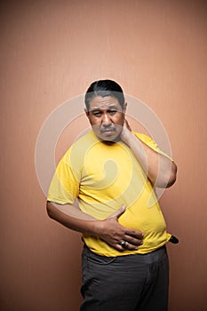 fat old asian man with distended abdomen touching his stomach