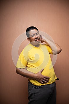 fat old asian man with distended abdomen touching his stomach