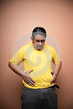 fat old asian man with distended abdomen touching his stomach