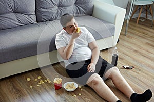 Fat overweight teenager boy has bad nutrition, eat unhealthy food photo