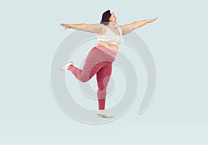 Fat overweight woman wearing sportswear doing fit exercise isolated on studio blue background.