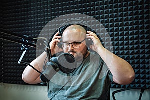 Fat radio presenter or host in radio station studio with headphones and microphone, portrait of working man