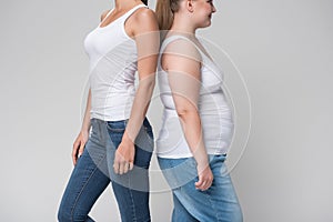 Fat and slim young women standing together