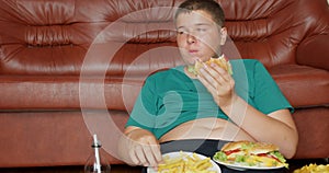 Fat teenager boy eating hamberger fast food . Breakfast for overweight person.