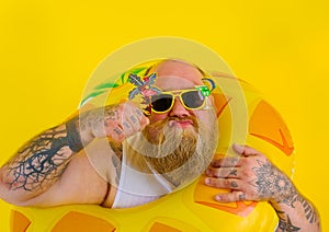 Fat thoughtful man with wig in head is ready to swim with a donut lifesaver