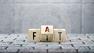 Fat versus Fit concept with words on wooden blocks with revolving letter depicting options, choices and a healthy or unhealthy