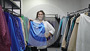 A fat woman chooses clothes to try on in a plus size store.