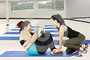 Fat woman doing sit up with a trainer