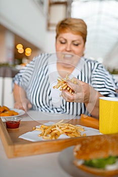 Fat woman eating high calorie food in mall