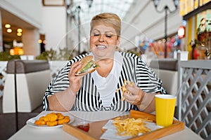 Fat woman eating high calorie food in restaurant