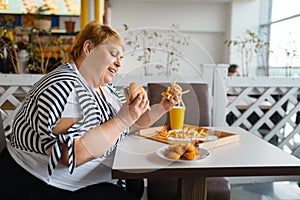 Fat woman eating high calorie food in restaurant