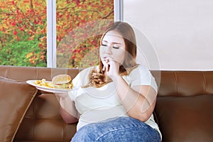 Fat woman eating junk food on the couch