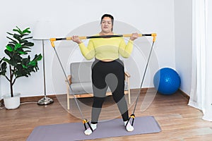 fat woman exercising at home with the use of assistive devices tighten the muscles