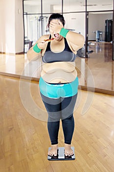 Fat woman facing health irony in the gym