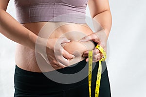 Fat woman, fat belly, chubby, obese woman hand holding excessive belly fat with measure tape, woman diet lifestyle concept