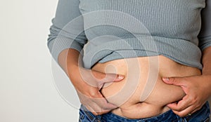 Fat woman hand holding excessive belly fat in uncomfortable jeans