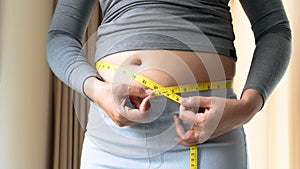 Fat woman hand holding measurement tape on her belly fat. woman diet lifestyle and build muscle concept