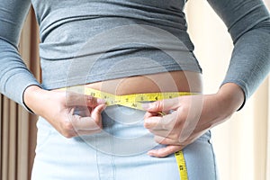 Fat woman hand holding measurement tape on her belly fat. woman diet lifestyle and build muscle concept