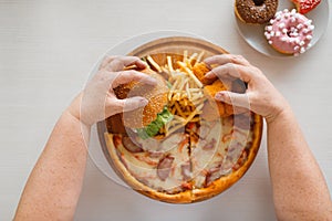 Fat woman hands against high calorie food