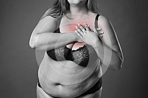 Fat woman with heart attack, pain in chest, overweight female body on gray background