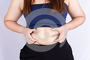 Fat woman holding excessive fat belly isolated grey background