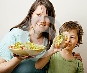 Fat woman holding salad and little cute boy with hamburger