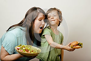 Fat woman holding salad and little cute boy with hamburger