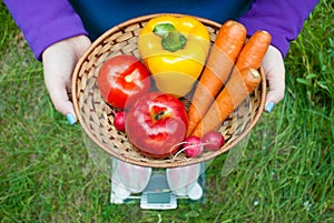 Fat woman holds a wicker basket brown with vegetables