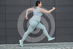 Fat woman jogging, doing sports for weight loss, obesity problem.