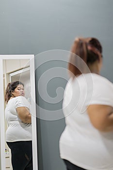 Fat woman looking at her body in the mirror