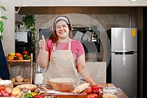 Fat woman making traditional italian pizza in kitchen at home.