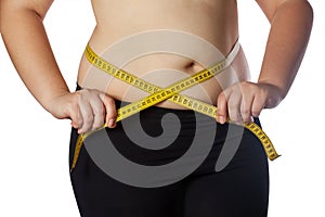 Fat woman measuring her waist with a yellow measuring tape. Reduction of overweight and obesity treatment. photo