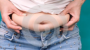 Fat woman, Obese woman hand holding excessive belly fat isolated on green background, Overweight fatty belly of woman