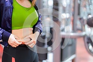 Fat woman, Obese woman hand holding excessive belly fat isolated on gym background