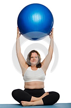 Fat woman practicing yoga with blue ball