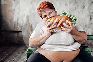 Fat woman sits in chair and eats sandwich, bulimic