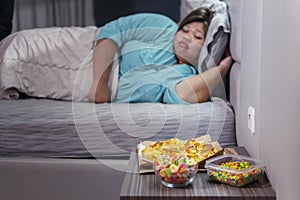 Fat woman sleeping while her junk foods lying