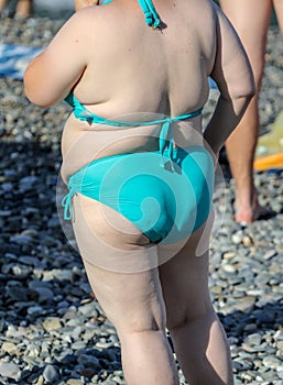 Fat woman in swimsuit on the sea beach